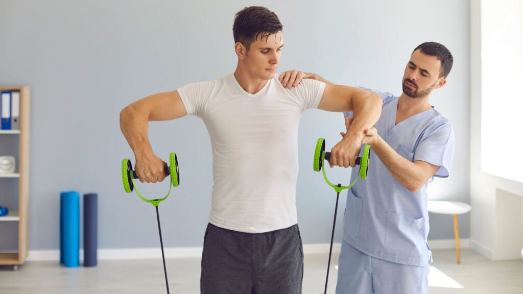 A therapist in blue scrubs helps a patient perform shoulder exercises with resistance bands in a bright, calming room, focusing on rehabilitation.